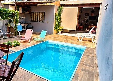 Piscina com espreguiçadeiras e mesa no quintal da pousada