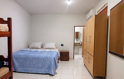 Quarto com cama de casal, beliche, guarda-roupa e banheiro